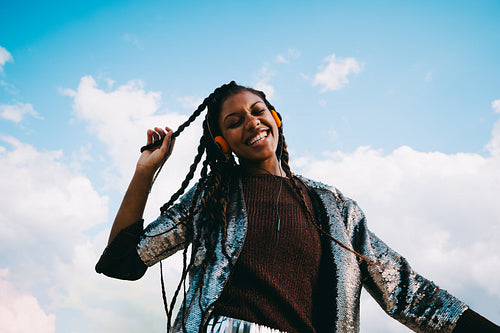 Woman enjoys music on headphones beneath a blue sky