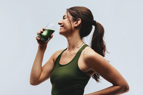 Woman drinking green superfood drink in studio