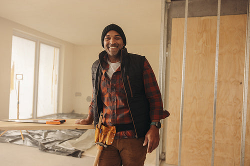 DIY enthusiast with a tool belt standing in kitchen, ready to renovate and upgrade his home interior