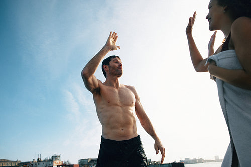 The celebration begins as swimming friends share a high five on the dock.