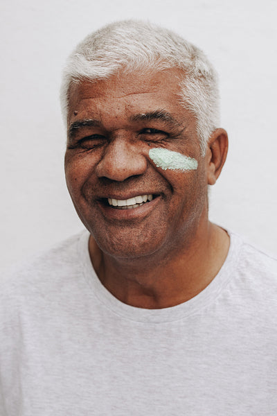 Happy mature man applying a beauty product on his face