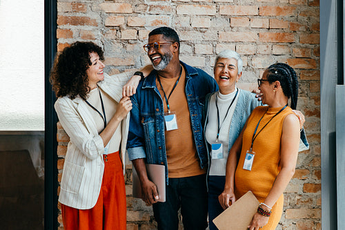 Multiethnic colleagues enjoying a casual conversation and laughter at work, showcasing diversity and teamwork in a positive office environment
