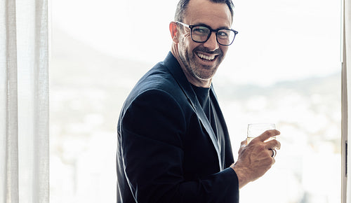 Smiling businessman having a drink in hotel room