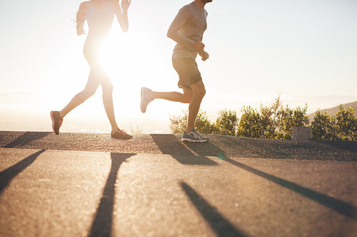 Two people running on country road at sunrise