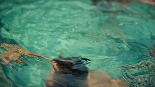 Boy learning to swim in a vibrant blue pool while on a relaxing family vacation