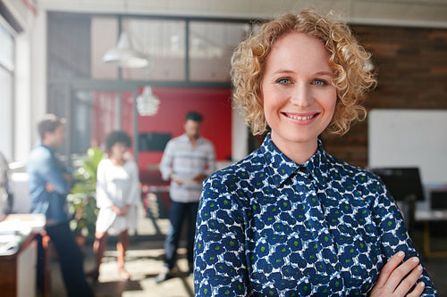 Female designer with colleagues in the background at office