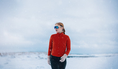 Cold weather running shows the woman training through winter snowfall outdoors