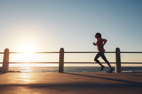 Sportswoman running on a road by the sea