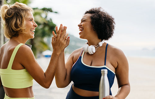 Fitness friends celebrating with a high five after a beach workout session