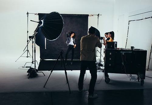 Photographer with his crew during a photo shoot in studio.