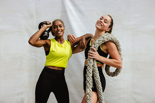 Two sports women with kettlebell and battle rope