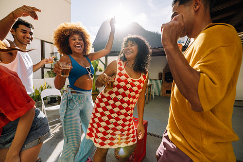 Group of friends dancing and enjoying a sunny rooftop gathering
