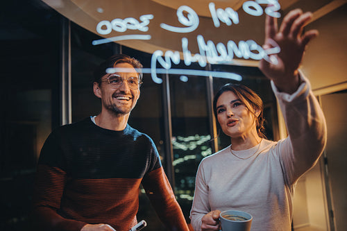 Two business people having a late night business meeting in a glass-walled office