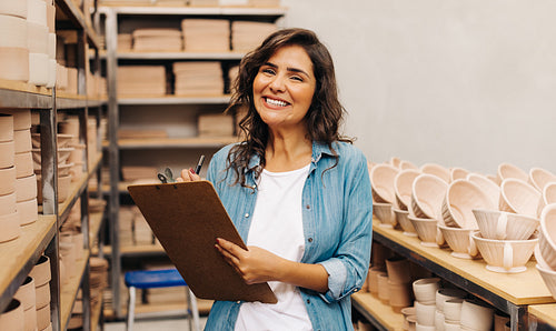 Happy female ceramist smiling at the camera in her shop
