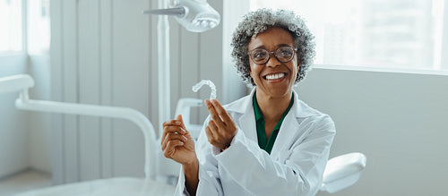 Dental aligner consultation with smiling woman in orthodontic clinic holding clear retainer