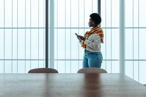 Successful African-American entrepreneur standing confidently with smartphone