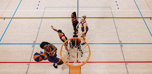 Basketball players competing in a gym jumping for a basket shot