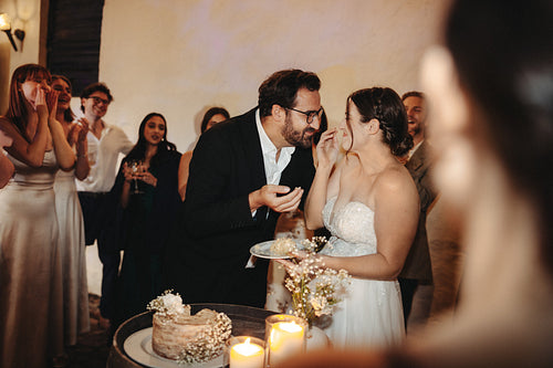Bride and groom laughing during cake cutting at wedding party