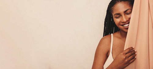 Smiling young woman standing behind a studio curtain