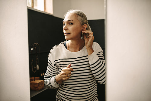 Senior woman trying on a ear ring at jewelry store