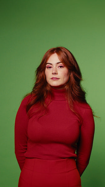 Young woman in red turtleneck and skirt in studio with green screen