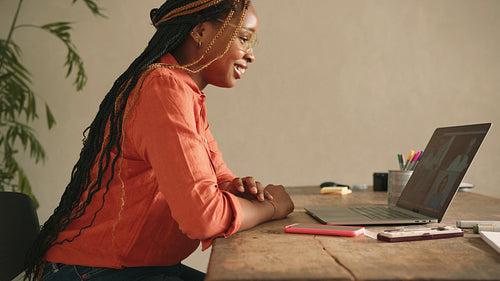 Smiling designer attending virtual meeting in her home office