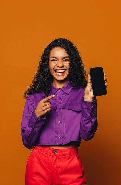 Cheerful woman recommending vibrant fashion on orange background