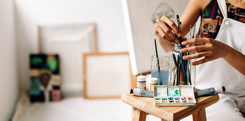 Anonymous female painter picking a brush from a jar