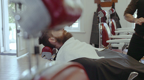 Barber styling beard with scissors at barbershop