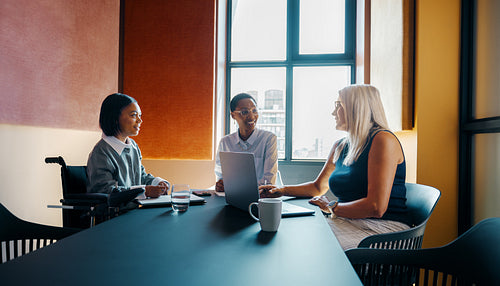 Three diverse women discussing ideas in an office meeting space
