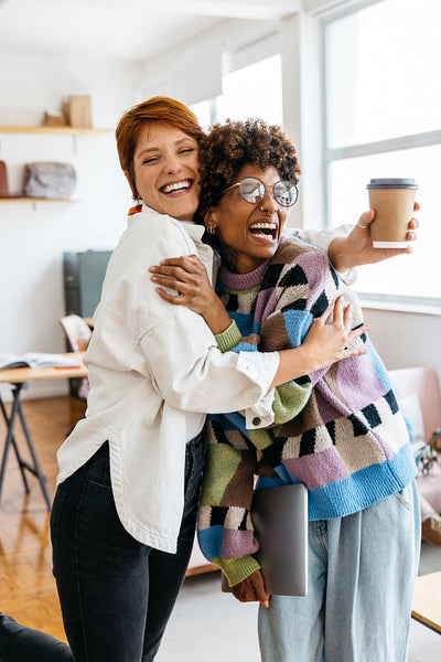 Colleagues embracing in a modern freelance co-working space
