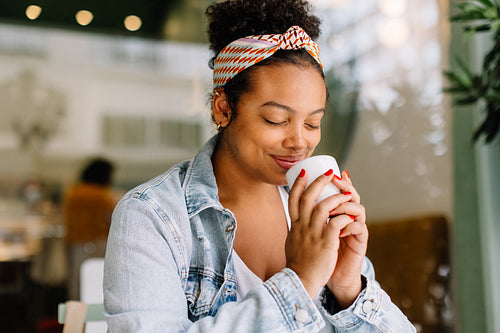 Happy smiling woman enjoying refreshing beverage at cafe