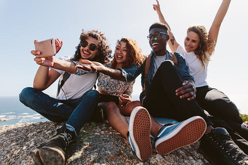 Friends sitting on top of a mountain taking selfie
