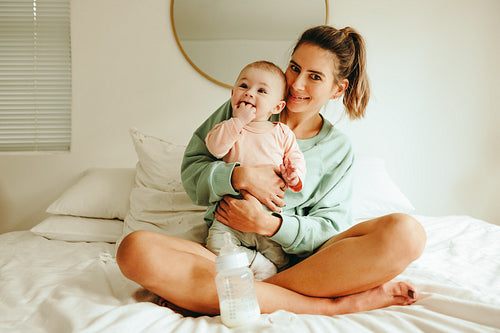 Happy mother holding her baby on the bed