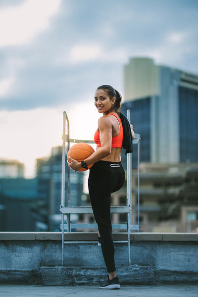 Fitness woman standing on rooftop holding a basketball