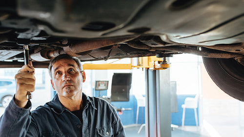 Mechanic fixing exhaust system of a car