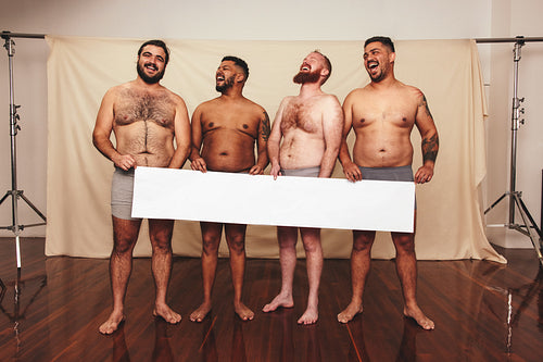 Smiling men holding a white banner in a studio