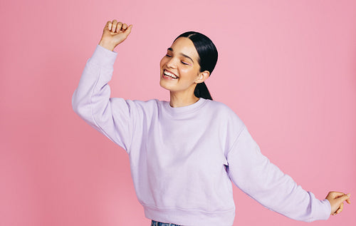 Joyful dance in the studio: Young woman celebrating and moving to the rhythm of music