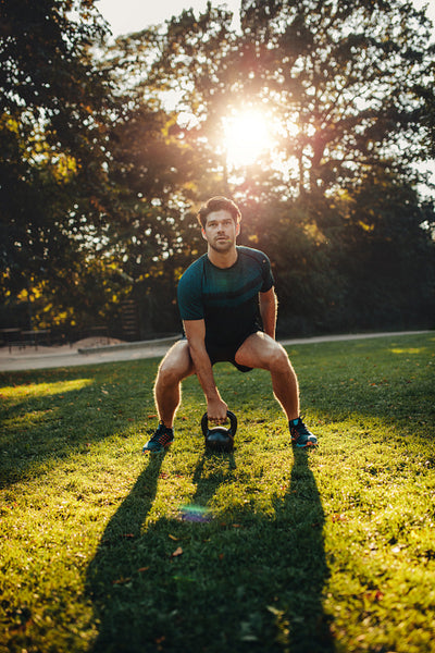 Strong man exercising with kettle bell in the park
