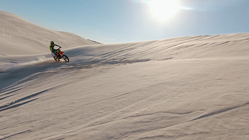 Motorcyclist leaning his bike over sand dunes