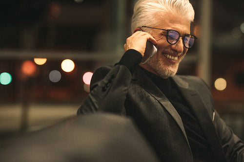 Mature businessman talking on cellphone in office