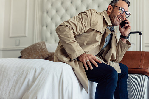 Successful businessman in hotel room talking on mobile phone