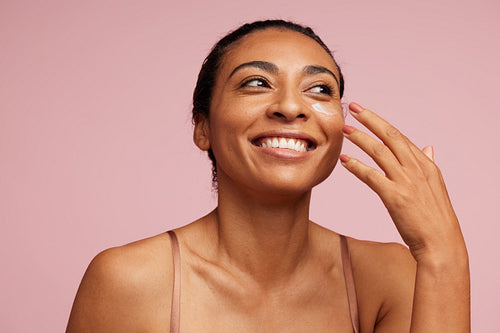 Woman applying face cream and smiling