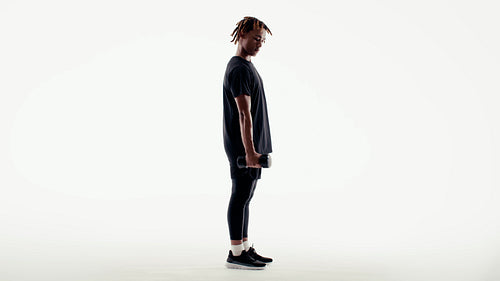 Young man performs intense bicep curls with dumbbells in a striking studio silhouette