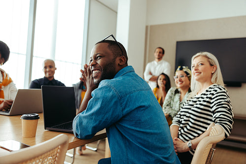 Smiling African-American businessman in a lively meeting with diverse colleagues