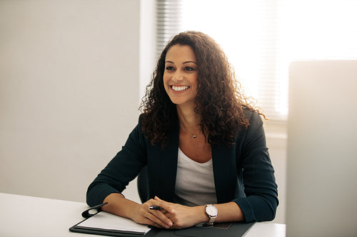 Smiling businesswoman sitting at her desk in office