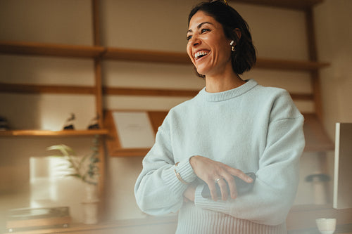 Smiling professional woman stands with folded arms in an office setting