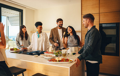 Friends enjoying a lively conversation and meal preparation in a stylish kitchen