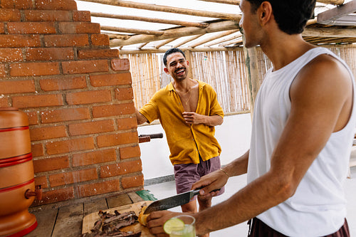 Two men socializing while preparing Brazilian barbecue outdoors together