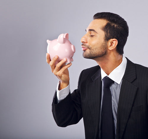 Handsome Executive Kissing a Coin Bank